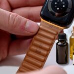 apple leather watch band in a hand and some essential oils for cleaning it in background
